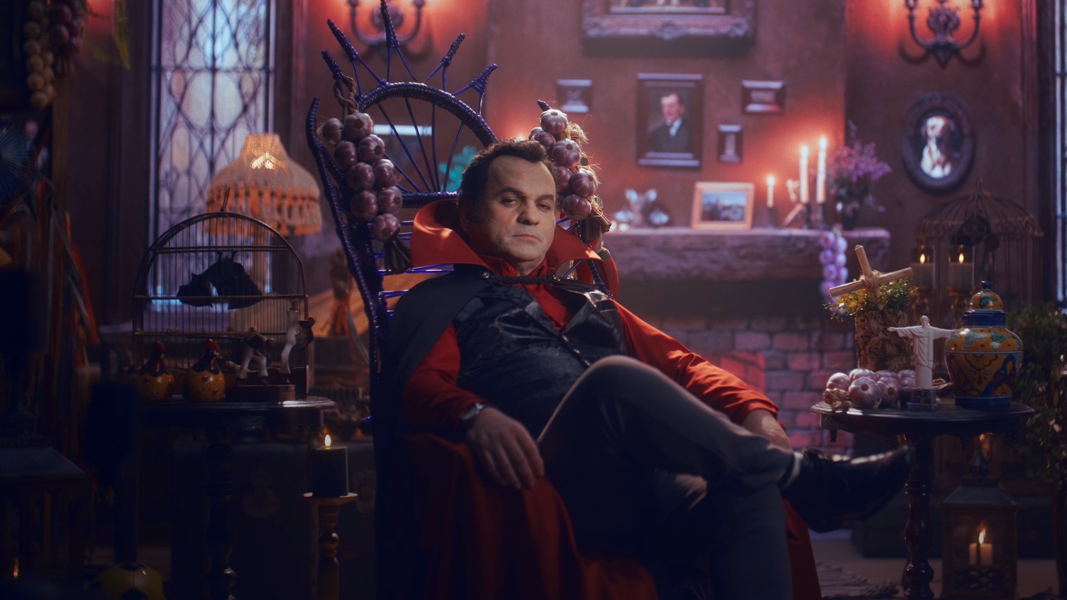 Conde Alhyson, o mascote vampiro da Santa Massa, sentado em seu trono em castelo iluminado de vermelho